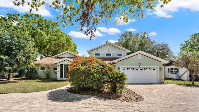 view of front of home with a front yard, decorative driveway, an attached garage, and stucco siding