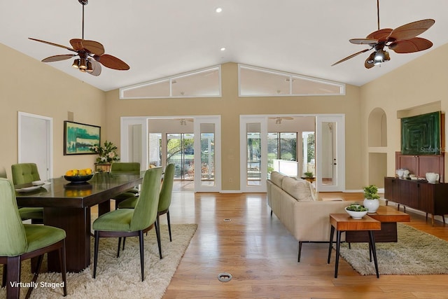 living area with high vaulted ceiling, light wood-type flooring, ceiling fan, and baseboards