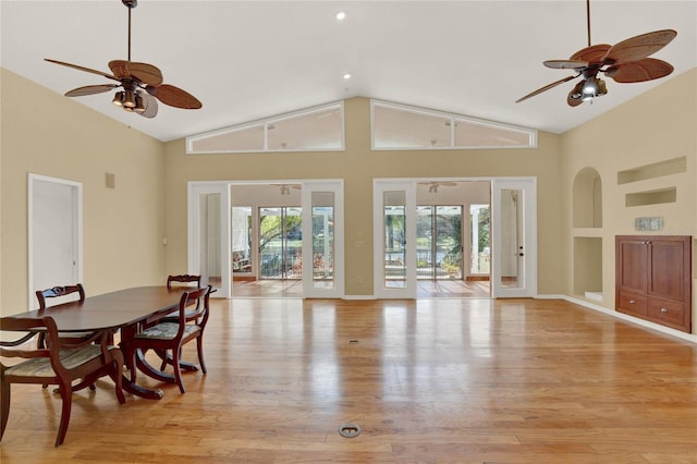 dining space with built in shelves, ceiling fan, light wood-style flooring, and high vaulted ceiling