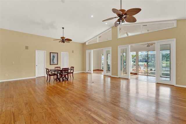 unfurnished living room featuring high vaulted ceiling, light wood-style flooring, baseboards, and a ceiling fan