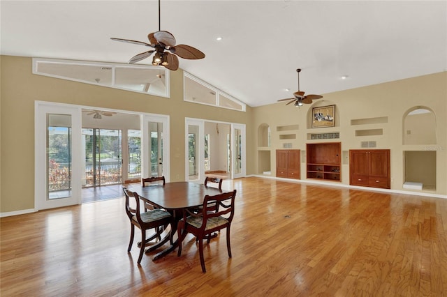 dining area with ceiling fan, high vaulted ceiling, light wood-style flooring, visible vents, and baseboards