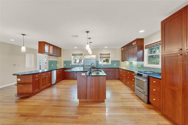 kitchen featuring stainless steel appliances, dark countertops, pendant lighting, and a peninsula