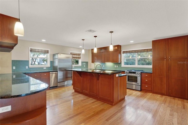 kitchen with appliances with stainless steel finishes, light wood-type flooring, visible vents, and hanging light fixtures