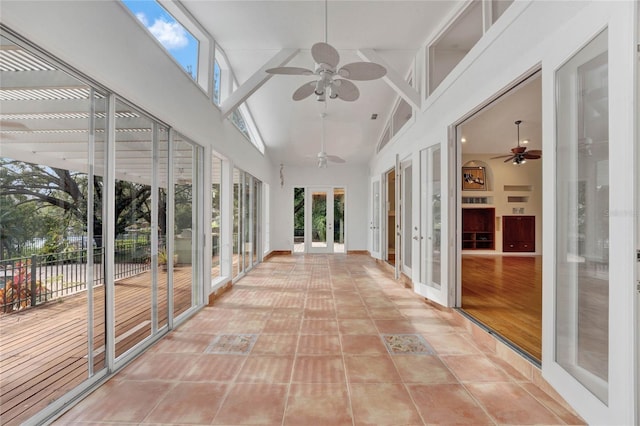 unfurnished sunroom with plenty of natural light, vaulted ceiling, a ceiling fan, and french doors