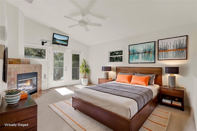 bedroom with vaulted ceiling, access to outside, ceiling fan, and a tile fireplace