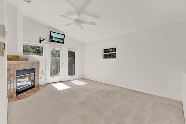 unfurnished living room with a tile fireplace, light colored carpet, a ceiling fan, vaulted ceiling, and french doors