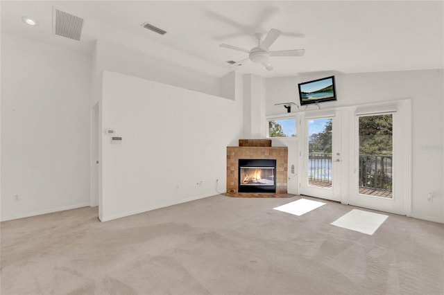 unfurnished living room with light colored carpet, visible vents, and a tiled fireplace