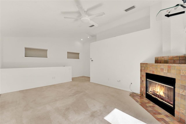 unfurnished living room with light carpet, visible vents, a ceiling fan, a tiled fireplace, and lofted ceiling