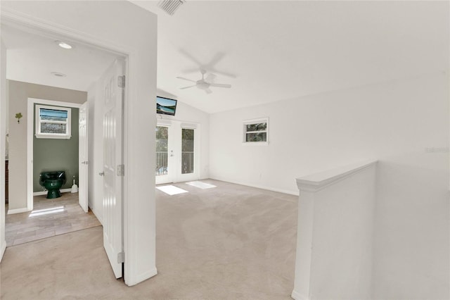 spare room with light carpet, visible vents, lofted ceiling, ceiling fan, and french doors