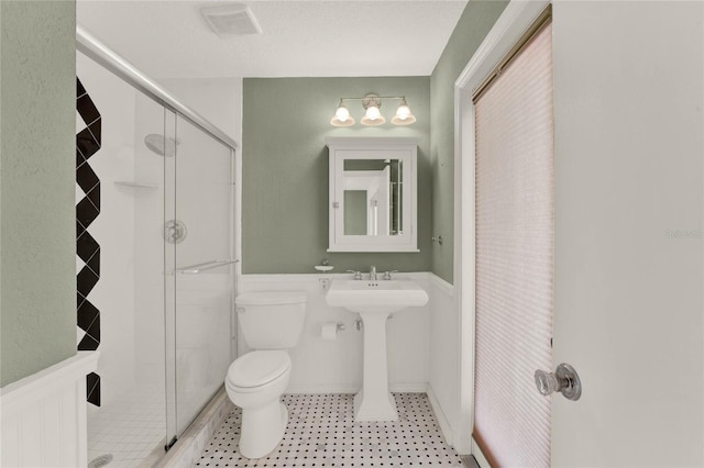 bathroom with toilet, a stall shower, and visible vents