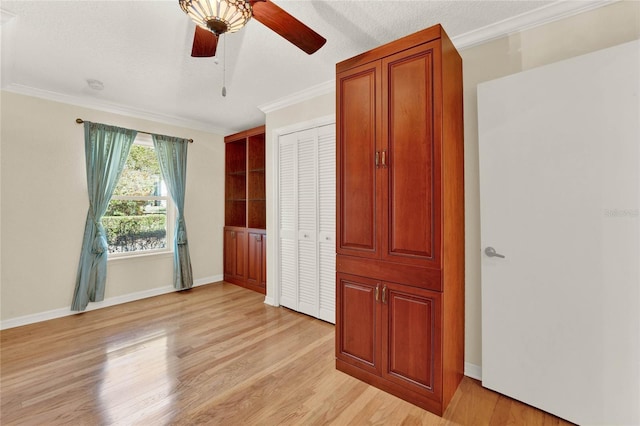 unfurnished bedroom with a textured ceiling, a ceiling fan, baseboards, light wood finished floors, and crown molding