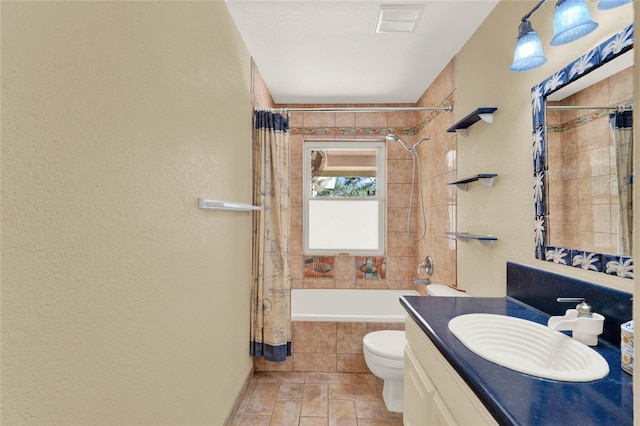 full bathroom with visible vents, a textured wall, toilet, tiled shower / bath, and vanity