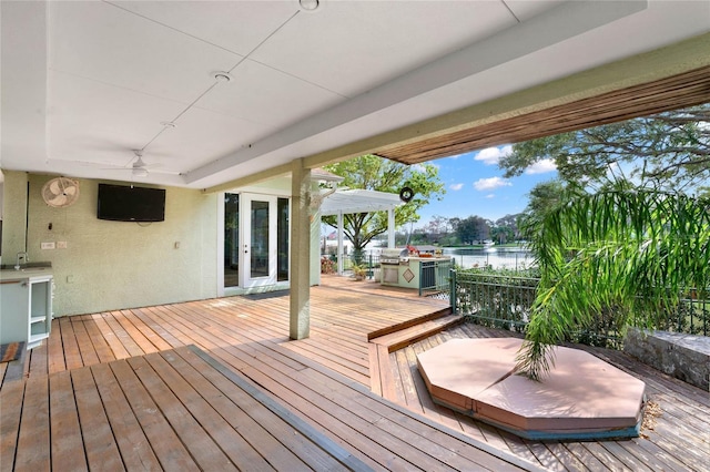 deck with french doors, a water view, ceiling fan, and a pergola