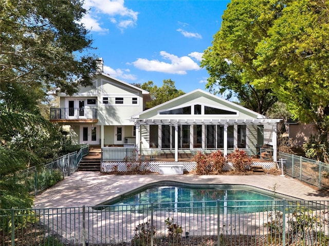 rear view of property featuring a fenced in pool, a patio area, and fence