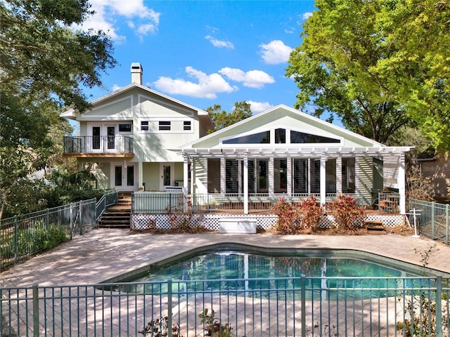 rear view of property featuring a fenced in pool, fence, a chimney, and a patio