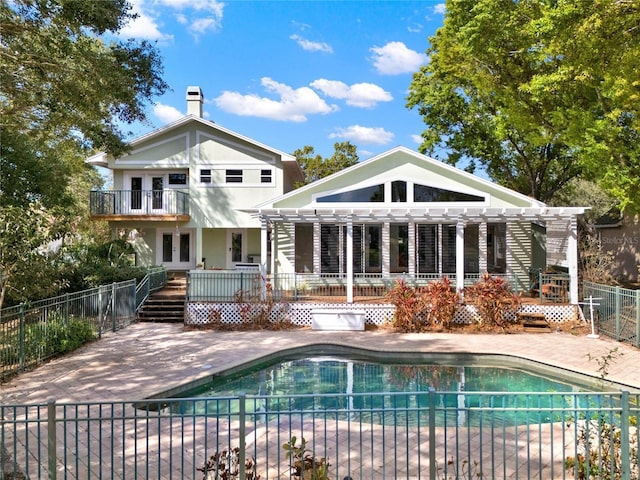 rear view of property featuring a patio area, fence, and a fenced in pool