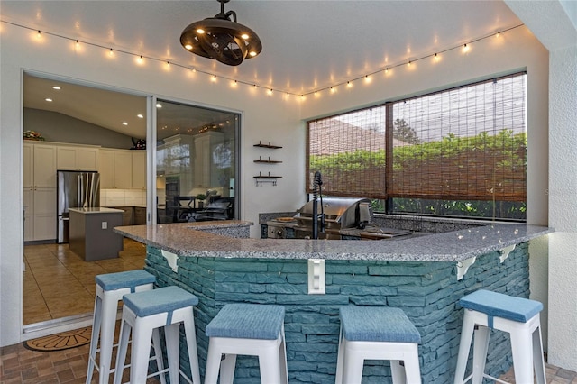 kitchen with white cabinets, a kitchen island, a breakfast bar, freestanding refrigerator, and hanging light fixtures