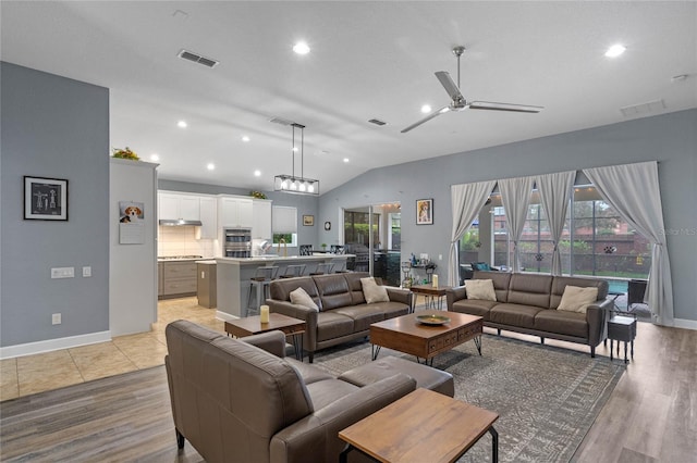 living area featuring vaulted ceiling, a ceiling fan, visible vents, and light wood-style floors