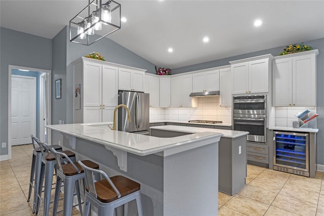 kitchen featuring a spacious island, beverage cooler, appliances with stainless steel finishes, and white cabinets