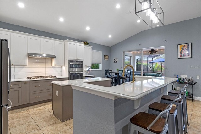 kitchen featuring a spacious island, a breakfast bar area, stainless steel appliances, light countertops, and white cabinetry