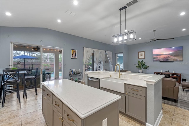 kitchen with visible vents, a kitchen island, light countertops, gray cabinetry, and a sink