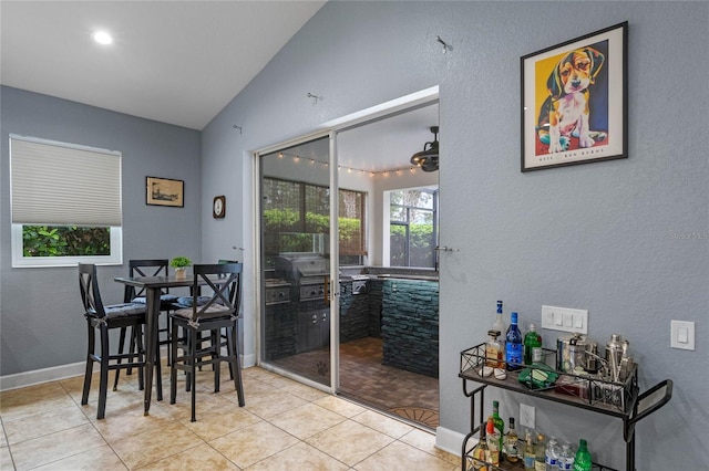 dining room featuring lofted ceiling, baseboards, and light tile patterned floors