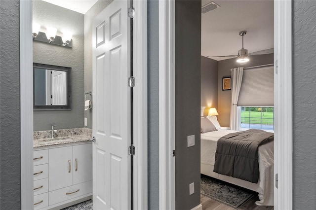 bathroom featuring a textured wall, visible vents, wood finished floors, and vanity