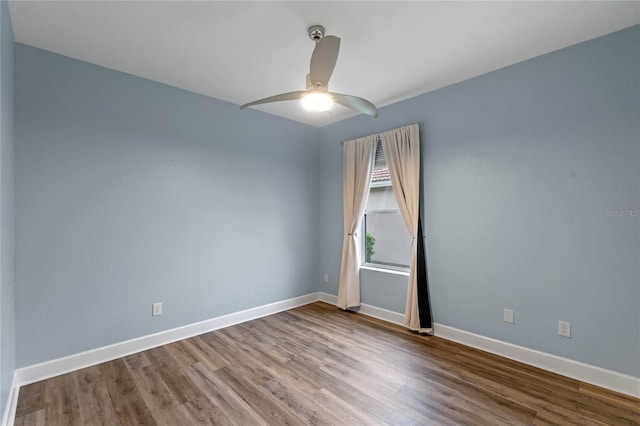 spare room with wood finished floors, a ceiling fan, and baseboards