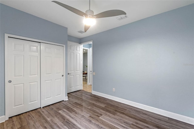 unfurnished bedroom featuring a closet, visible vents, baseboards, and wood finished floors