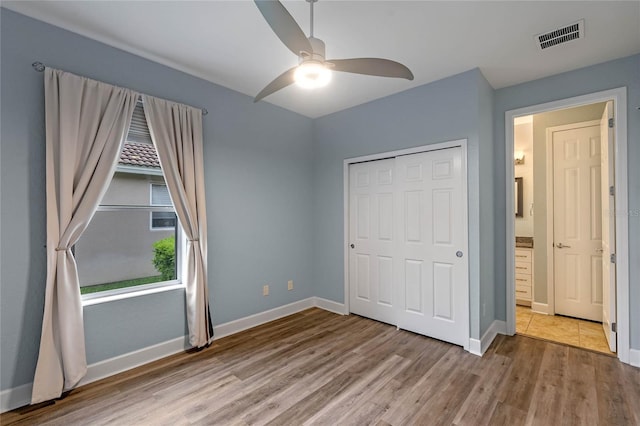 unfurnished bedroom with baseboards, visible vents, ceiling fan, light wood-style floors, and a closet