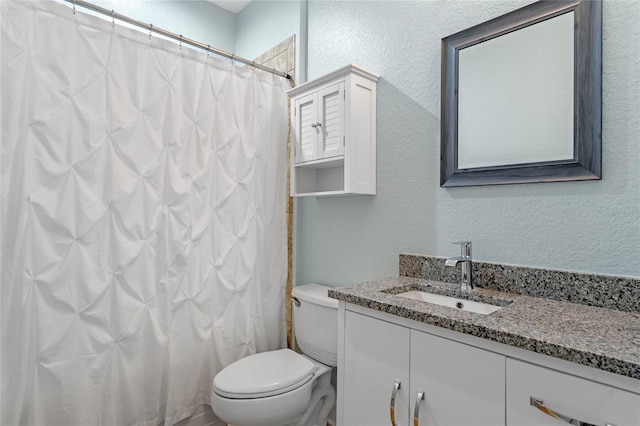 bathroom featuring toilet, a shower with curtain, vanity, and a textured wall