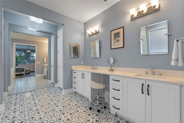 ensuite bathroom with double vanity, a sink, baseboards, and ensuite bathroom