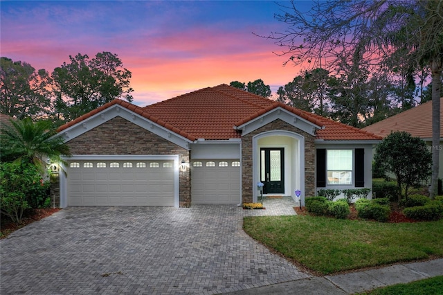 view of front facade featuring a garage, stone siding, decorative driveway, and a tiled roof