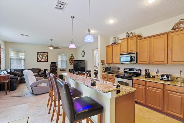 kitchen with stainless steel appliances, hanging light fixtures, open floor plan, an island with sink, and a kitchen bar