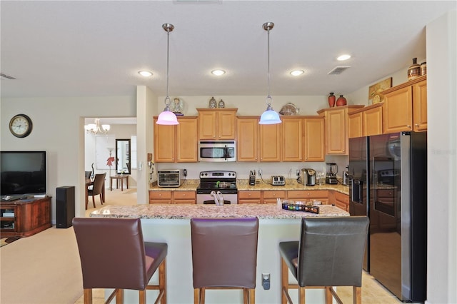 kitchen featuring stainless steel appliances, visible vents, hanging light fixtures, light stone countertops, and a center island with sink