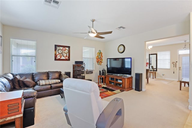 living area with a healthy amount of sunlight, visible vents, and light carpet