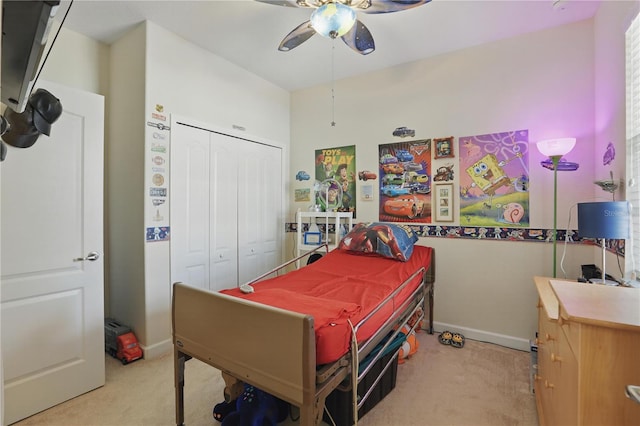 bedroom with a ceiling fan, a closet, light colored carpet, and baseboards