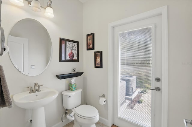 half bathroom with toilet, baseboards, and a sink