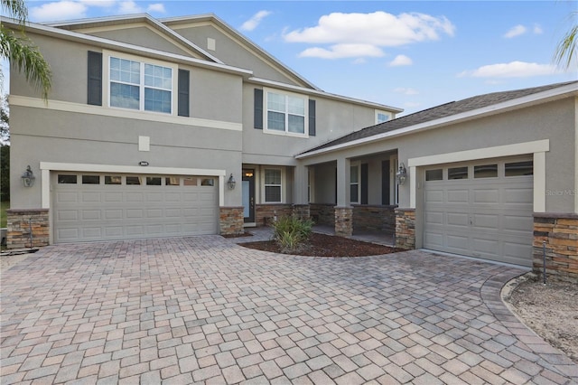 view of front facade with stone siding, decorative driveway, and stucco siding