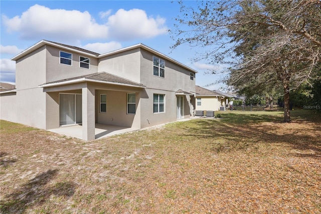 rear view of property featuring a patio area, a lawn, and stucco siding