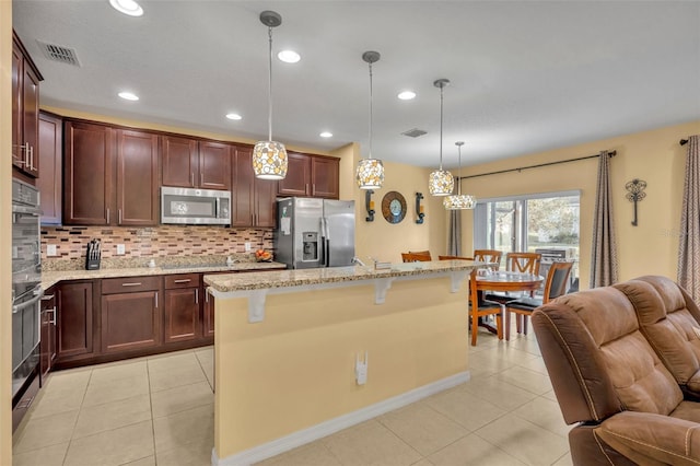 15506 Gemini Dr, Mascotte, FL 34753 - kitchen with a kitchen island with sink, hanging light fixtures, stainless steel appliances, and a kitchen breakfast bar