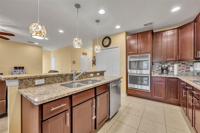 15506 Gemini Dr, Mascotte, FL 34753 - kitchen featuring sink, a kitchen island with sink, hanging light fixtures, stainless steel appliances, and decorative backsplash