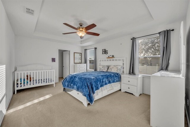 15506 Gemini Dr, Mascotte, FL 34753 - bedroom featuring light colored carpet, a raised ceiling, and ceiling fan