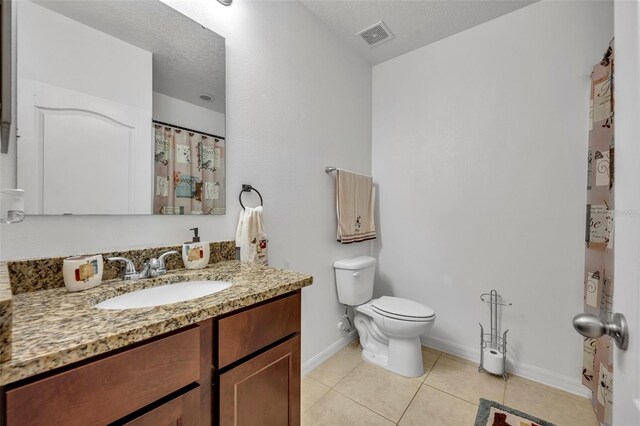 15506 Gemini Dr, Mascotte, FL 34753 - bathroom with vanity, tile patterned floors, a textured ceiling, and toilet