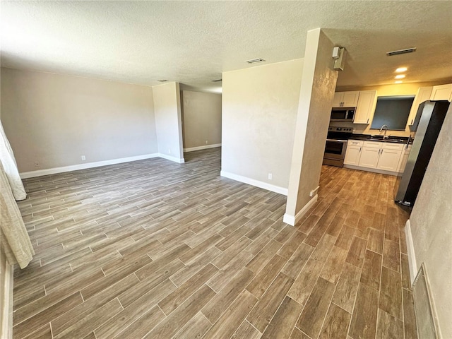 interior space with wood finish floors, dark countertops, appliances with stainless steel finishes, and open floor plan