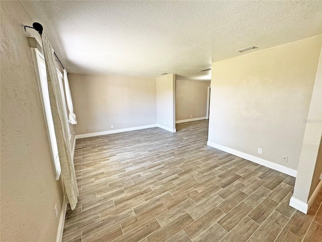 empty room featuring visible vents, baseboards, and wood finish floors