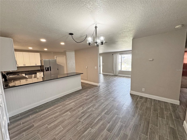 kitchen featuring stainless steel appliances, dark countertops, open floor plan, and wood tiled floor