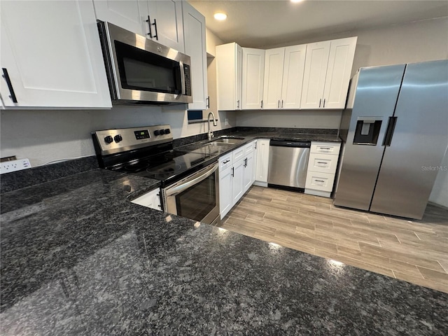 kitchen featuring wood finish floors, dark stone counters, recessed lighting, appliances with stainless steel finishes, and a sink