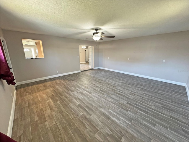 spare room featuring dark wood-type flooring, a ceiling fan, baseboards, and a textured ceiling