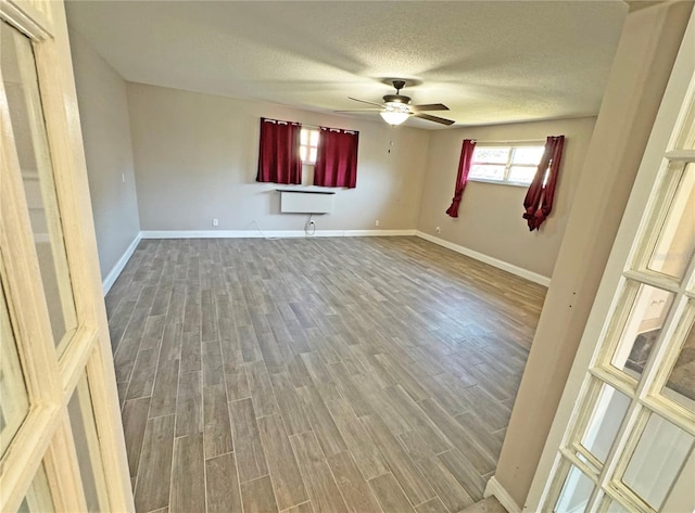 spare room with ceiling fan, baseboards, a textured ceiling, and wood finished floors